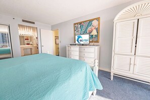 A hotel room with a bed, a vanity with lights, a television, and a wardrobe. - South Hampton 3BR Oceanview,Balcony,Steps to Beach (Myrtle Beach)