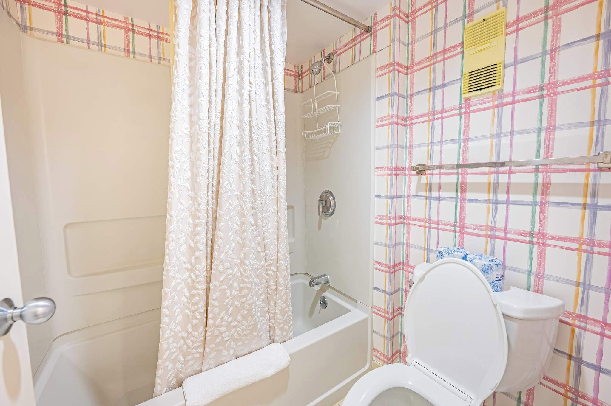 A bathroom with a bathtub, toilet, and shower area.