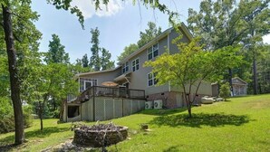 A two-story house with a covered porch, a fenced yard, and a small tree in the foreground. - Well-appointed 5-bedroom, 5 bathroom house on gorgeous Lake Wateree with AC (Ridgeway)