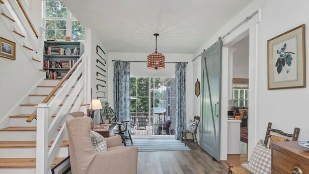 A spacious living area with a wooden staircase, a sofa, a wooden chair, and a dining table. - Well-appointed 5-bedroom, 5 bathroom house on gorgeous Lake Wateree with AC (Ridgeway)