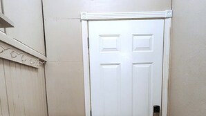 A narrow hallway with a white door, a wooden bench, and a white chair. - Comfortable 2BR Near Lakewalk with Private Entry & Parking (Duluth)