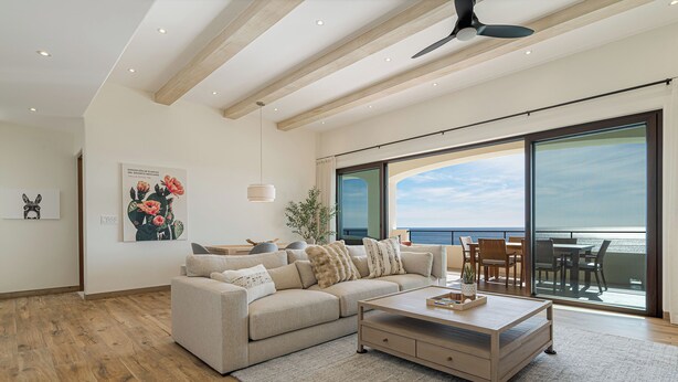Ein geräumiges Wohnzimmer mit einer großen Couch, einem Couchtisch und Meerblick durch große Fenster.
