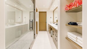 Ein modernes Badezimmer mit Glasdusche, Holztür und einem Handtuchhalter mit ordentlich gefalteten Handtüchern.
