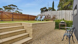 A backyard with a wooden fence, a set of steps leading to a patio area, and outdoor furniture. - The Studio | A Slower Stay in Normanville | 5 Mins to the Beach (normanville)