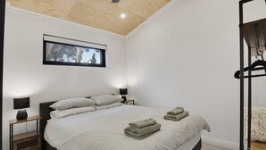 A bedroom with a bed, two bedside tables with lamps, a window, and a ceiling light. - The Studio | A Slower Stay in Normanville | 5 Mins to the Beach (normanville)