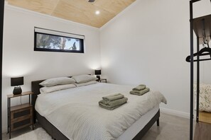 Ein Schlafzimmer mit einem Bett, zwei Nachttischen mit Lampen, einem Fenster und einer Deckenleuchte.