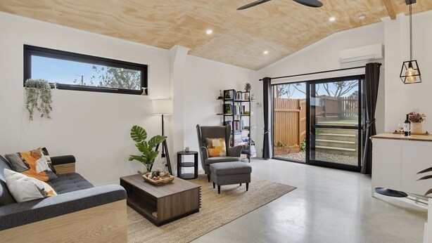 Una sala moderna con sofá, sillón, mesa de centro y estantería.