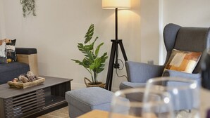 Una sala de estar moderna con un sofá, una mesita de centro, una lámpara de pie y una planta en maceta.
