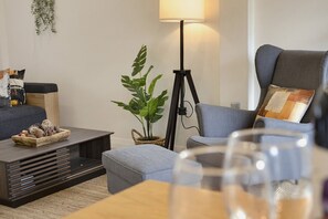 Ein modernes Wohnzimmer mit einer Couch, einem Couchtisch, einer Stehlampe und einer Topfpflanze.