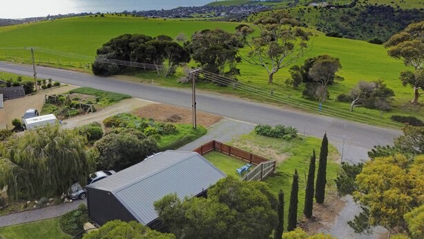A residential area with a road, a fenced yard, and a building with a metal roof. - The Studio | A Slower Stay in Normanville | 5 Mins to the Beach (normanville)
