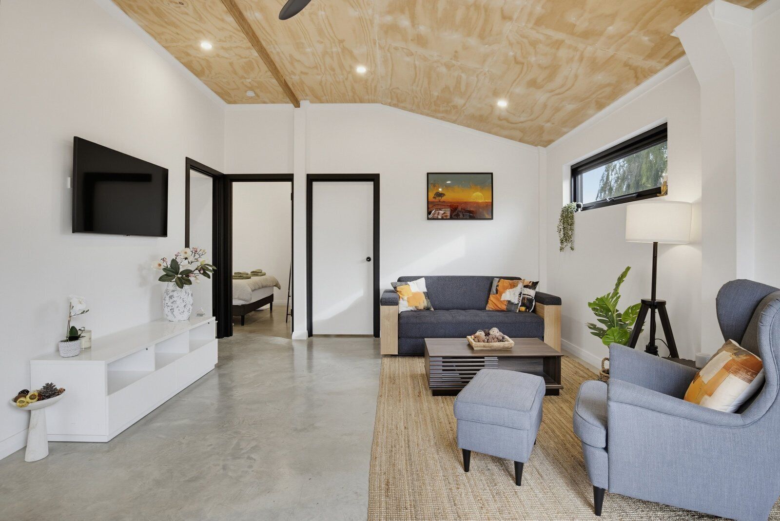 Un salon moderne avec un canapé, des fauteuils, une table basse, un téléviseur et un tableau accroché au mur.