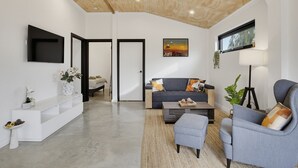 A modern living room with a sofa, armchairs, a coffee table, a TV, and a painting on the wall. - The Studio | A Slower Stay in Normanville | 5 Mins to the Beach (normanville)
