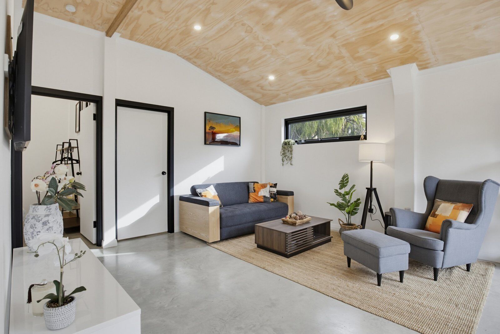 A modern living room with a sofa, armchair, coffee table, and a painting on the wall.
