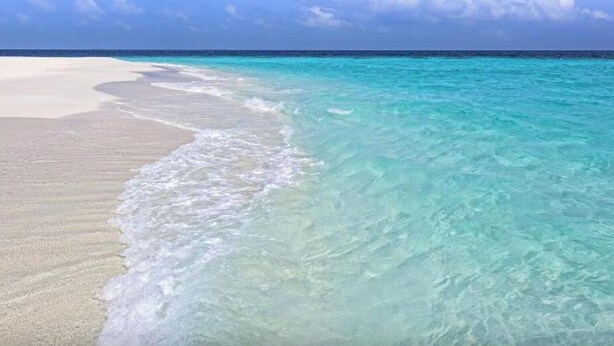 Een strand met helder turquoise water en wit zand.