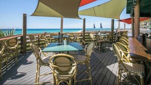 Een terras buiten met rieten meubels, een tafel en uitzicht op de oceaan.