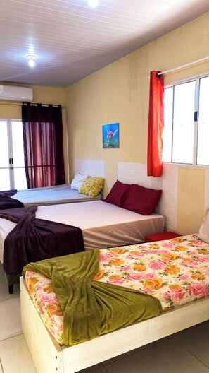 Habitació d'hotel amb dos llits, una finestra amb cortines, aire condicionat fixat a la paret i un quadre.