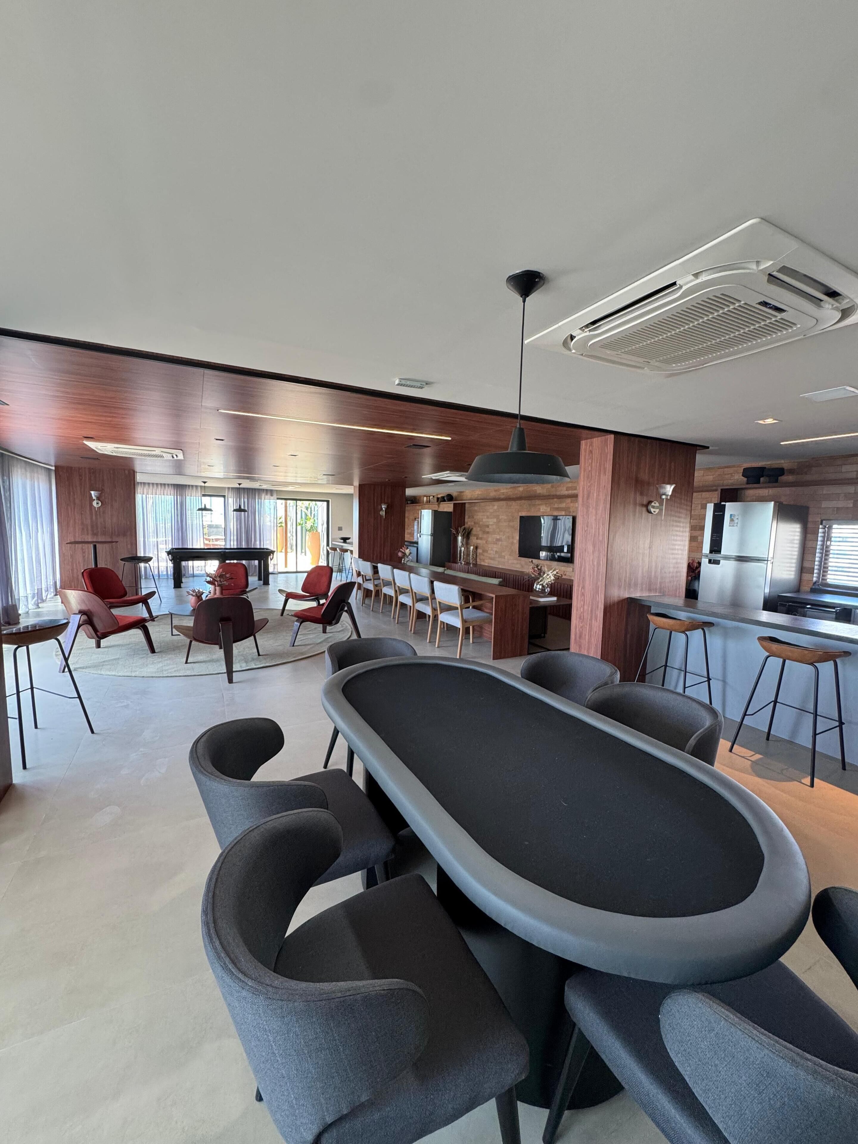 A modern kitchen with a central island, bar stools, and a dining area with chairs.