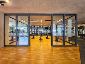 Ein modernes Fitnessstudio mit Trainingsgeräten, Glastüren und Holzboden.