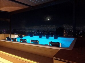 A rooftop pool with a city view at night, including a visible moon and distant city lights. - Edificio OA Aparta-suites (Medellín)