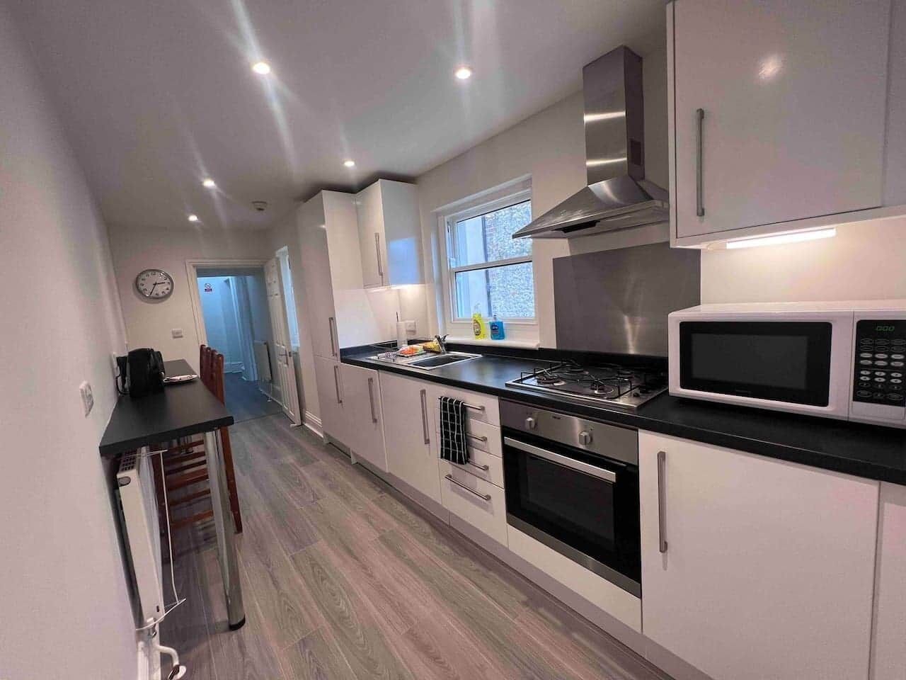 A modern kitchen with white cabinets, a black countertop, stainless steel appliances, and a window providing natural light.