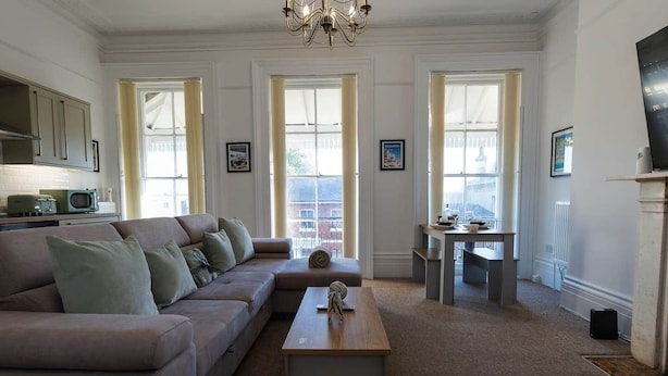 A living room with a sectional sofa, a coffee table, and a dining area with a table and chairs. - Spacious 2 Bed Apartment in Brighton with Parking (Brighton and Hove)