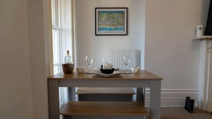 A dining area with a table and benches, a framed map on the wall, and a radiator. - Spacious 2 Bed Apartment in Brighton with Parking (Brighton and Hove)