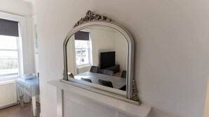 A room with a fireplace, a mirror, a dining table, and a window.
