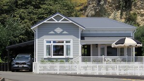A two-story building with a white picket fence, a covered porch, and a car parked in front.