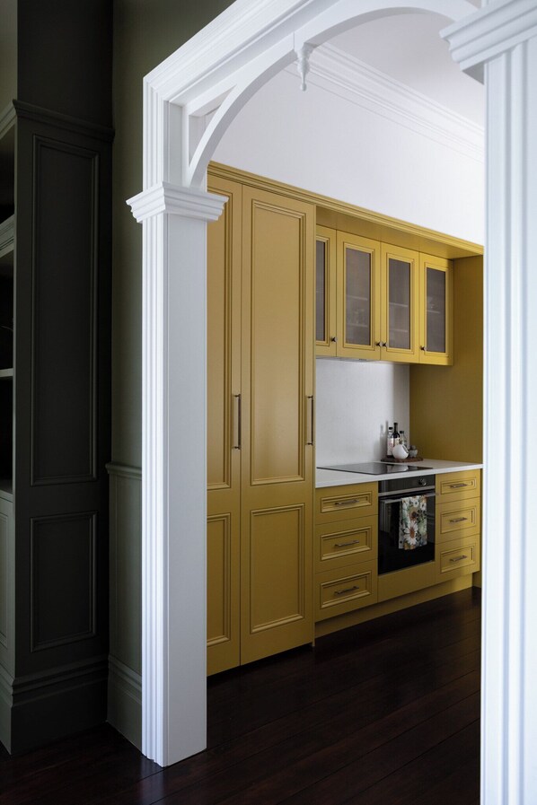 Una cocina con armarios amarillos, encimera blanca y suelo de madera oscura.