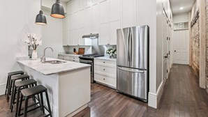 Una cocina moderna con armarios blancos, un refrigerador de acero inoxidable y una isla central con taburetes de bar.