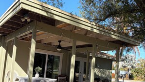 A covered patio area with a table and chairs, a ceiling fan, and a view of the backyard. - Fabulous Country Apartment in "America's Happiest Seaside Town." (Stuart)