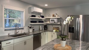 A modern kitchen with a granite countertop, stainless steel appliances, and a window with blinds. - Fabulous Country Apartment in "America's Happiest Seaside Town." (Stuart)