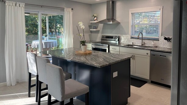 A modern kitchen with a central island, stainless steel appliances, and a view of the outdoors. - Fabulous Country Apartment in "America's Happiest Seaside Town." (Stuart)