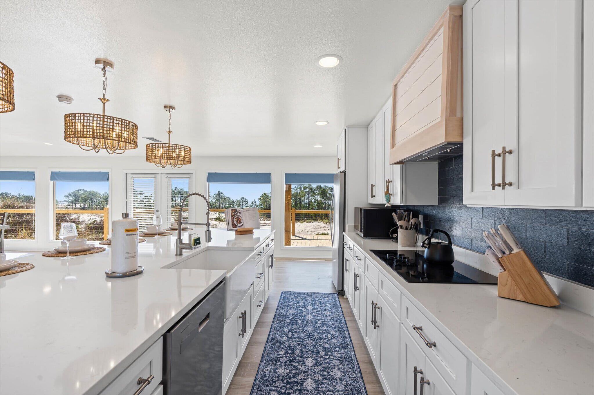 A modern kitchen with white cabinetry, a central island, and a view of the outdoors.