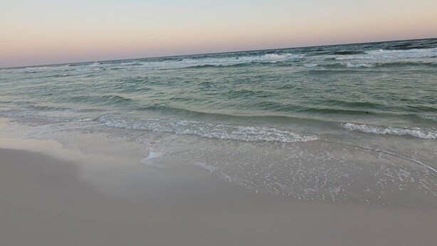 Uma praia com ondas e céu claro.