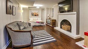 Een gezellige woonkamer met een bank, een open haard en een grote televisie.