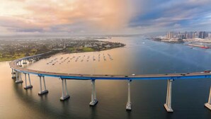 Een brede brug met meerdere rijstroken over een waterpartij, die twee landmassa’s verbindt.