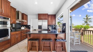 Une cuisine moderne avec des meubles en bois, des appareils électroménagers en acier inoxydable et un coin bar avec des tabourets.