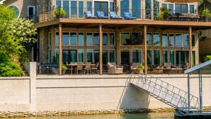 Una amplia propiedad frente al mar, de varios pisos, con balcón, mobiliario exterior y un muelle.