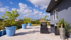 A patio area with outdoor furniture, large potted plants, and a view of a house in the background. - BK Villas Light House 4br/4ba sleeps 8 (Enterprise)