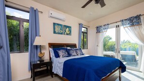 A bedroom with a large bed, a nightstand, a ceiling fan, and a view of the outdoors through a sliding glass door. - BK Villas Light House 4br/4ba sleeps 8 (Enterprise)