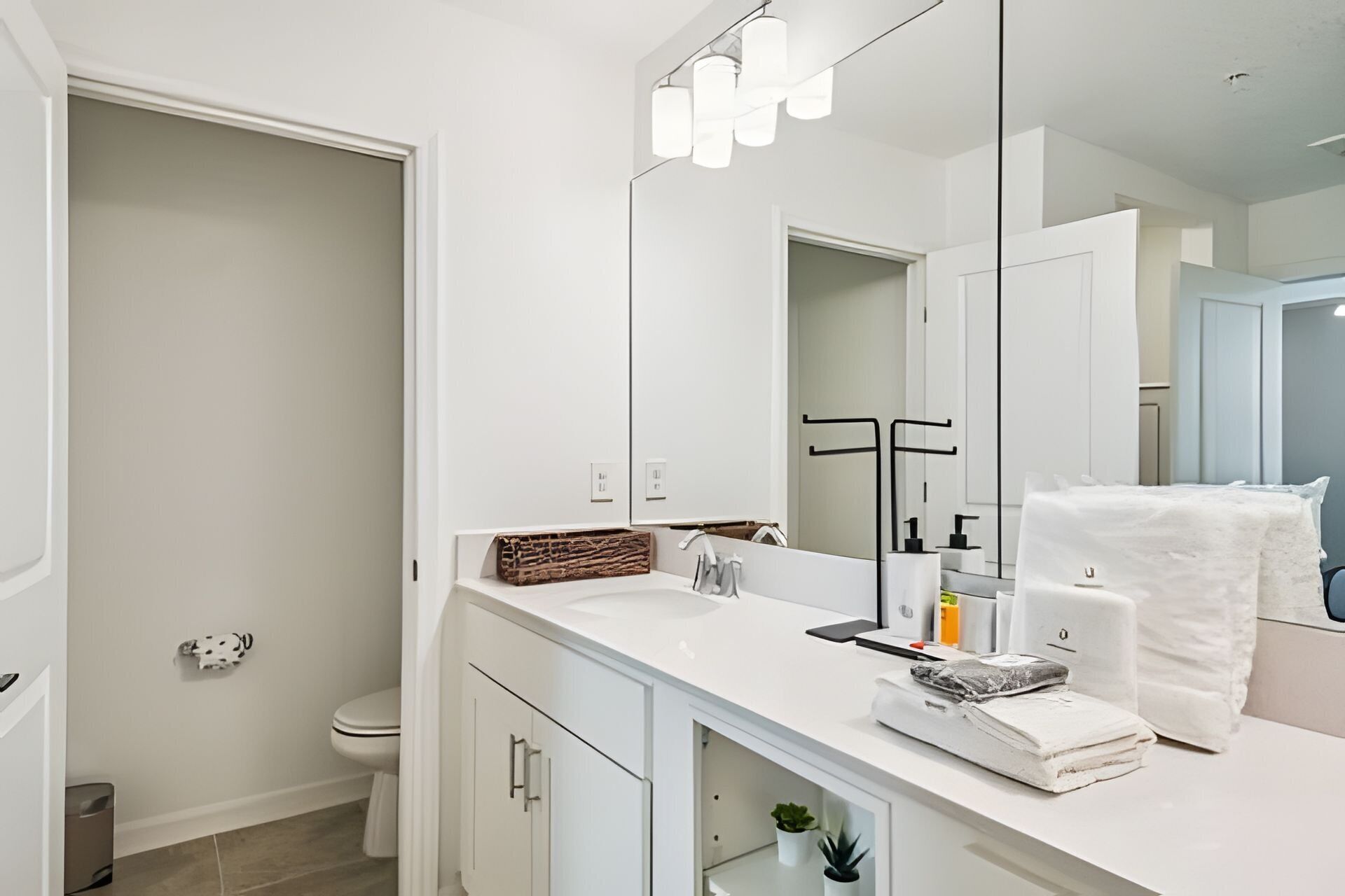 Een moderne badkamer met een wit wastafelmeubel, een grote spiegel en een handdoekhouder.