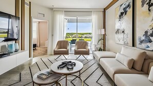 Een moderne woonkamer met een bank, twee fauteuils, een salontafel en een televisie.
