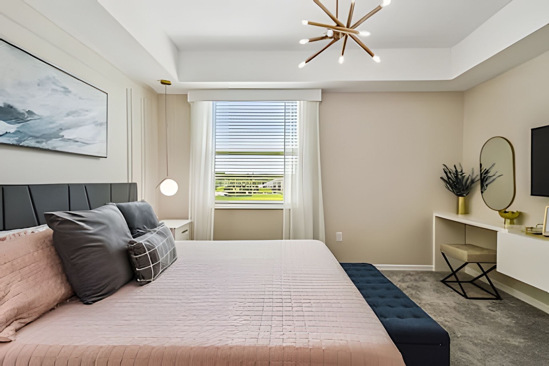 A modern bedroom with a large bed, a bedside table, a desk, a chair, a window with blinds, a ceiling light, and a wall-mounted mirror.