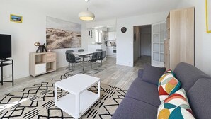 Una sala de estar moderna con un sofá, una mesa de centro, un televisor y un comedor con sillas y una mesa.