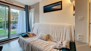 Ein Schlafzimmer mit einem großen Bett, einem Fenster mit Vorhängen, einem gerahmten Bild an der Wand und einem kleinen Tisch mit einer Lampe.