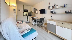 Ein kompakter Wohnbereich mit Küchenzeile, Essbereich und einer Sitzecke mit Sofa und Sessel.