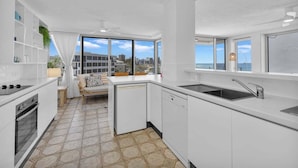 A modern kitchen with white cabinetry, a built-in oven, and a large window offering a city view. - 3 Bedroom Apartment Ocean View - Seamist (Kings Beach)
