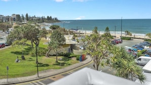 A coastal view with a parking area, greenery, and buildings in the background. - 3 Bedroom Apartment Ocean View - Seamist (Kings Beach)