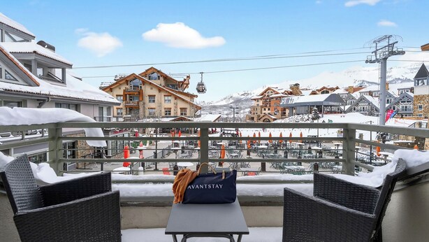 A balcony with wicker chairs, a table, and a snow-covered town in the background. - Blue Mesa Lodge 20B by Avantstay Prime Ski Access Condo Steps to Gondola, Lifts, & Dining (Telluride)